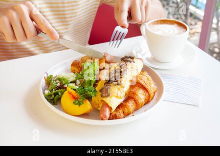 Sandwich brioche aux œufs croissants et saucisses avec fruits et légumes frais dans un café. Banque D'Images