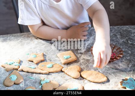 Un petit garçon décore des biscuits au gingembre sur la cuisine Banque D'Images