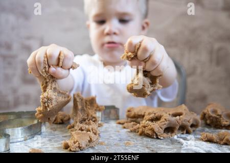 Le petit garçon pétrit la pâte pour les biscuits au gingembre Banque D'Images