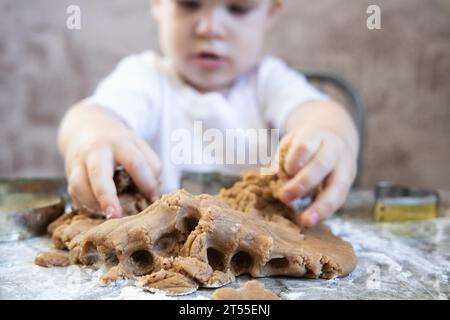 Le petit garçon pétrit la pâte pour les biscuits au gingembre Banque D'Images