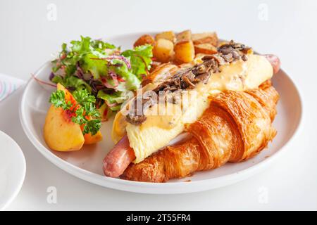 Sandwich brioche aux œufs croissants et saucisses avec fruits et légumes frais dans un café. Banque D'Images