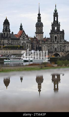 03 novembre 2023, Saxe, Dresde : les tours du Ständehaus (l-r), du Georgentor, du Hausmannsturm et de la Hofkirche se reflètent dans une flaque d'eau sur le Königsufer en face de la vieille ville sur l'Elbe, le bateau à aubes historique de la Saxon Steamship Company a accosté sur le Terrassenufer. Le vent et la pluie dominent la météo en Allemagne le week-end. Des orages isolés ne peuvent pas être exclus sur la mer du Nord, comme l’a rapporté vendredi le service météorologique allemand à Offenbach. L'influence de la basse pression ne se relâchera pas non plus dans la semaine à venir : elle restera douce, humide et orageuse par endroits. Banque D'Images