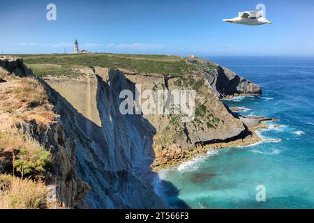 Une mouette survole les falaises rocheuses du cap Espichel. Bâtiment phare en bas, Sesimbra, Portugal Banque D'Images