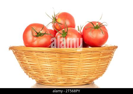 Plusieurs tomates juteuses roses dans un plat de paille, macro, isolées sur un fond blanc. Banque D'Images