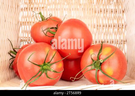 Plusieurs tomates juteuses roses dans un panier, macro. Banque D'Images