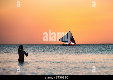 (Mise au point sélective) vue imprenable d'un bateau naviguant lors d'un beau coucher de soleil en arrière-plan et la silhouette d'une personne floue. Banque D'Images