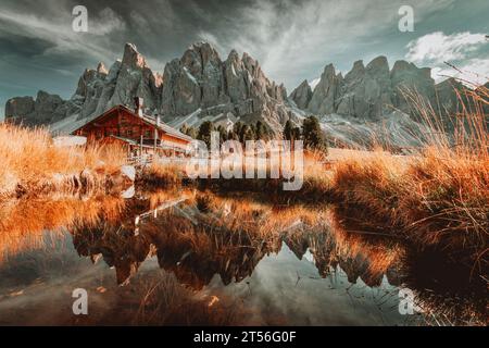 Vue panoramique de Geisler Alm Rifugio delle Odle en face des montagnes dolomites et reflet dans l'eau d'un étang, Tyrol du Sud, Italie Banque D'Images