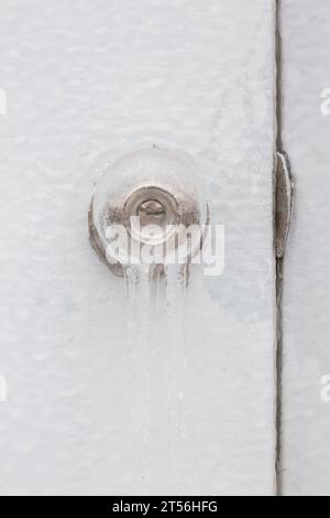 Gros plan d'une poignée de porte recouverte de glace avec trou de serrure et gâche sur porte blanche, Québec, Canada Banque D'Images