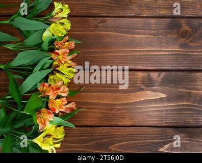 Fleurs jaunes et oranges Alstroemeria sur fond de bois brun foncé Banque D'Images