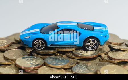 Une voiture miniature sur une pile de pièces. Banque D'Images