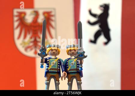 Potsdam, Allemagne. 03 novembre 2023. Deux personnages Playmobil avec des épées à la main se tiennent devant les drapeaux de Brandebourg et de Berlin lors d'une conférence de presse commune après la réunion du cabinet des États de Berlin et de Brandebourg. Crédit : Michael Bahlo/dpa/Alamy Live News Banque D'Images