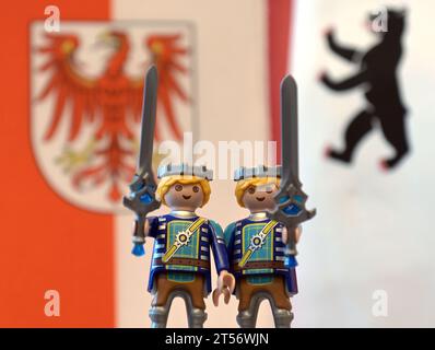 Potsdam, Allemagne. 03 novembre 2023. Deux personnages Playmobil avec des épées à la main se tiennent devant les drapeaux de Brandebourg et de Berlin lors d'une conférence de presse commune après la réunion du cabinet des États de Berlin et de Brandebourg. Crédit : Michael Bahlo/dpa/Alamy Live News Banque D'Images