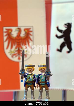 Potsdam, Allemagne. 03 novembre 2023. Deux personnages Playmobil avec des épées à la main se tiennent devant les drapeaux de Brandebourg et de Berlin lors d'une conférence de presse commune après la réunion du cabinet des États de Berlin et de Brandebourg. Crédit : Michael Bahlo/dpa/Alamy Live News Banque D'Images