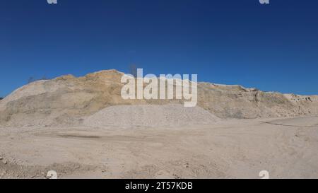 piles de pierre blanche et de sable sur un site minier, par une journée ensoleillée, contre un ciel bleu, carrière de calcaire avec des collines de roche extraite Banque D'Images