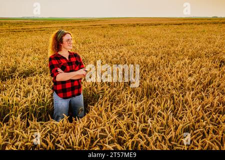 Portrait d'une agricultrice qui cultive du blé. Elle est satisfaite de la bonne progression des plantes. Occupation agricole. Banque D'Images