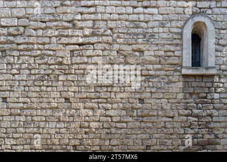 Vieux fond de mur en pierre avec fenêtre voûtée. Le fond texturé sera espacé pour le texte. Banque D'Images