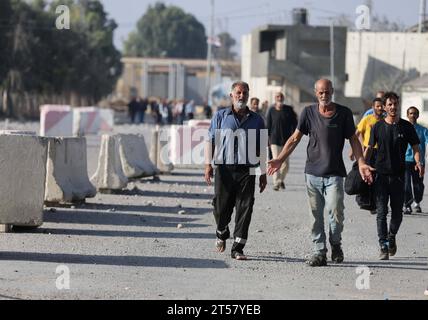 Les travailleurs palestiniens, bloqués en Israël depuis les attaques du 7 octobre, marchent près du poste frontière de Rafah. qui étaient bloqués en Israël depuis les attaques du 7 octobre, marchez près du poste frontalier de Rafah avec l’Égypte alors qu’ils font leur chemin pour rentrer dans la bande de Gaza au poste frontalier commercial de Kerem Shalom avec Israël dans le sud de l’enclave palestinienne le 3 novembre 2023. Photo de STR APAimages Rafah Cisjordanie territoire palestinien 031123 Rafah STR 0012 Copyright : xapaimagesxSTRxAPAimagesx crédit : Imago/Alamy Live News Banque D'Images