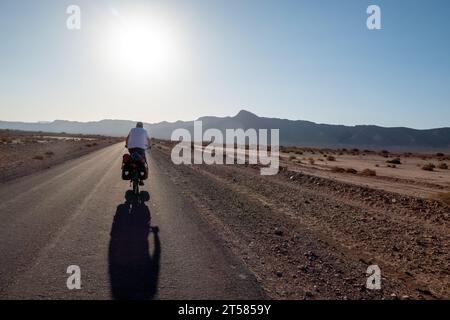 Cycliste sur la route du désert dans le sud du Maroc Banque D'Images