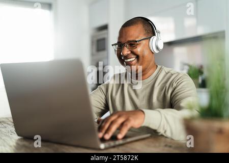 Heureux homme latin mature utilisant un ordinateur portable à la maison - technologie et concept de travail intelligent Banque D'Images