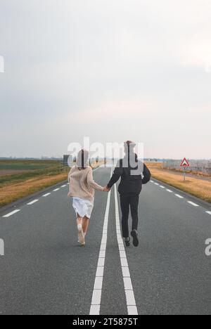 Un jeune couple amoureux court ensemble pour rencontrer de nouvelles aventures à Almere, aux pays-bas, au coucher du soleil. Banque D'Images