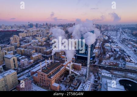 De la fumée s'échappe du tuyau de la chaudière. Système de chauffage central des immeubles d'appartements. Coucher de soleil en hiver Banque D'Images