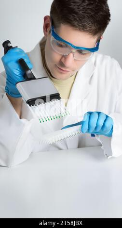 Un homme en blouse de laboratoire tenant une pipette multicanaux. Jeune biologiste mettant en place une réaction PCR Banque D'Images