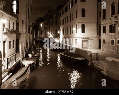 Les chaloupes sont amarrées dans un canal à Venise, en Italie, la nuit. Noir et blanc. Banque D'Images