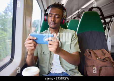 Young Man se rend au travail assis sur le train Streaming et regarder un film ou une émission sur téléphone portable Banque D'Images