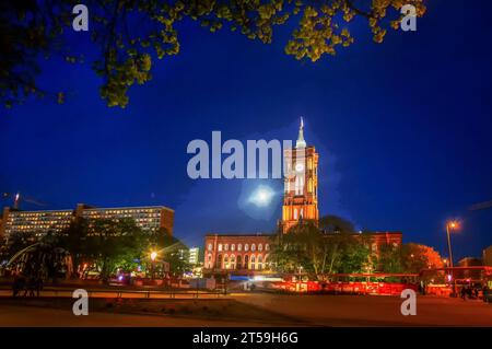 Incroyable tour de l'horloge de l'Hôtel de ville de Berlin ( Rotes Rathaus) et pleine lune derrière. Personnes en mouvement flou Banque D'Images