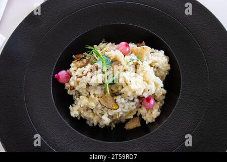 Risotto aux truffes et échalotes sur une assiette noire Banque D'Images