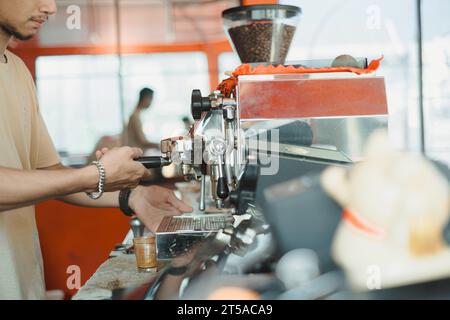 Un homme asiatique prépare un café à l'aide d'une machine à expresso automatique Banque D'Images