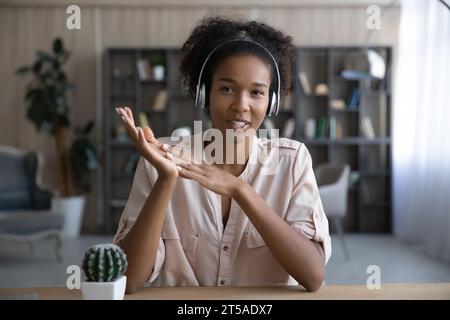 Heureux présentateur afro-américain féminin dans les écouteurs donnant webinaire Banque D'Images