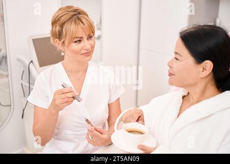 Le client parle autour d'une tasse de café avec le maquilleur permanent Banque D'Images