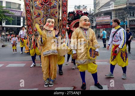 Prenant part à une fête taoïste à Bangkok, en Thaïlande, un couple thaïlandais se présente en tenue traditionnelle chinoise et avec des masques chinois souriants Banque D'Images