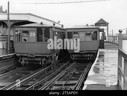 Deux trains électriques sur le Liverpool Overhead Railway à la gare de Seaforth Sands, Merseyside, Angleterre, Royaume-Uni vers 1950. Les trains à carrosserie en bois numéro 20 et 27 indiquent «Dingle», la gare terminus à l’autre bout de la ligne, sur leurs panneaux de destination. Le Liverpool Overhead Railway opérait le long des quais de Liverpool et ouvrit ses portes en 1893. C’était le premier chemin de fer électrique surélevé au monde et le deuxième plus ancien métro électrique au monde. À son apogée, près de 20 millions de personnes utilisaient le chemin de fer chaque année. Un rapport de 1955 a montré qu'il nécessitait des réparations inabordables et le chemin de fer a fermé en 1956. Banque D'Images