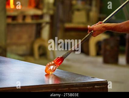 Un souffleur en verre de Murano contient une sculpture de cheval en verre chaud rouge Banque D'Images