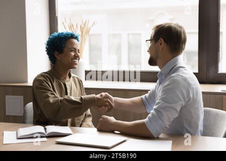 Joyeux couple de collègues de bureau serrant la main, riant Banque D'Images