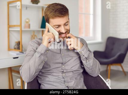 Souriant bel homme d'affaires parlant par téléphone portable dans le bureau Banque D'Images