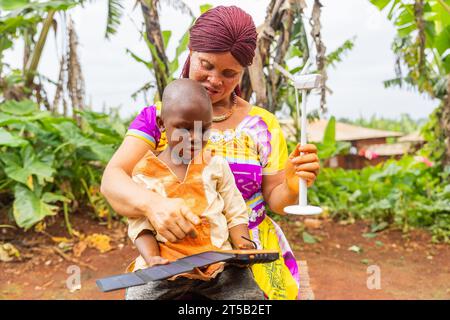 Dans une main, la mère tient l'éolienne et de l'autre montre à l'enfant les panneaux solaires. Banque D'Images