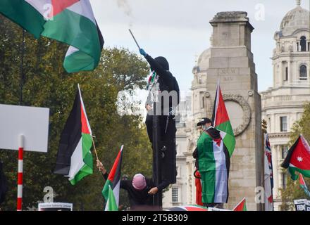 Londres, Royaume-Uni. 21 octobre 2023. Un manifestant grimpe à un feu de circulation et déclenche un feu d'artifice à côté du cénotaphe à Whitehall. Des dizaines de milliers de personnes ont défilé dans le centre de Londres en solidarité avec la Palestine alors que la guerre Israël-Hamas s’intensifie. Banque D'Images
