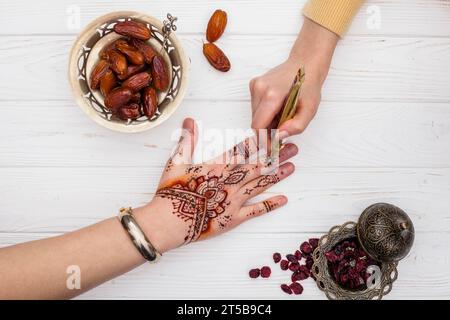 Artiste faisant mehndi womans main près des dates fruit Banque D'Images