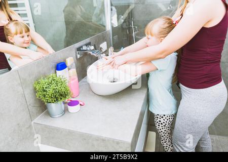 Mère de récolte aidant sa fille à se laver les mains Banque D'Images