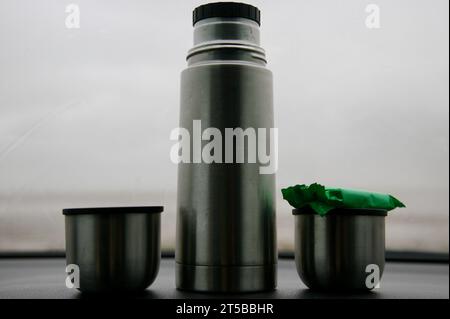 Piégé dans la voiture, au bord de l'eau, un jour humide et venteux, avec deux tasses de café et un biscuit au chocolat Banque D'Images