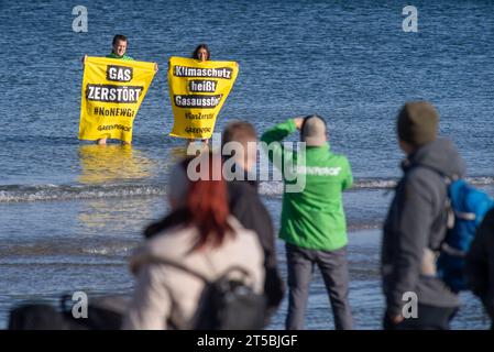 04 novembre 2023, Mecklembourg-Poméranie occidentale, Binz : les militants de Greenpeace se tiennent sur la plage de la mer Baltique avec des banderoles indiquant "gaz détruit" et "protection du climat signifie élimination progressive du gaz!". Non loin du site du terminal GNL prévu dans le port de Mukran sur la jetée de Binz, environ 100 personnes manifestent contre le projet, selon les rapports de police. Récemment, il y a eu de plus en plus de spéculations sur les raisons possibles d'un démarrage beaucoup plus tardif du terminal GNL de Rügen et des indications présumées à ce sujet. Les autorités et un développeur de projet contredisent cela. Der Spieg Banque D'Images