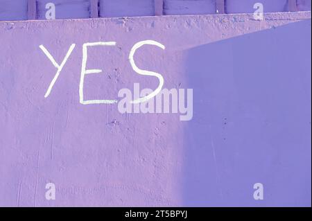 Le mot Oui peint sur un mur pourpre Banque D'Images