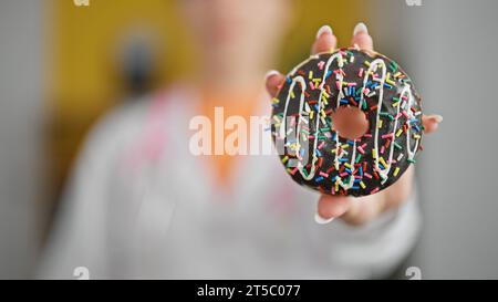 Jeune femme blonde diététicienne tenant un beignet à la clinique Banque D'Images