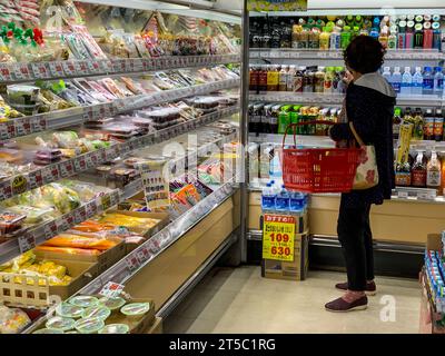 Japon, Kyushu, IMI. Petite épicerie, Shopper sélectionnant une boisson. Banque D'Images