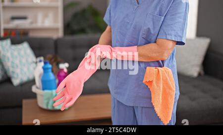 Nettoyeur professionnel femme d'âge moyen portant des gants à la maison Banque D'Images