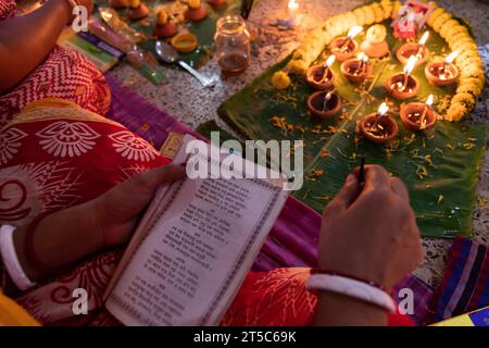 Dhaka, Bangladesh. 4 novembre 2023. Les dévots hindous s'assoient avec Prodip (lumières) et prient Dieu pour le bien-être de la famille devant le temple Shri Shri Lokanath Brahmachari Ashram, Swamibag, Dhaka pendant le Kartik Brati ou Rakher Upobash, un festival religieux hindou de jeûne organisé chaque année à la dernière moitié du mois bengali Kartik. Les dévots s'assoient avec de la nourriture et des bougies et prient sincèrement le Dieu avant de rompre le jeûne. Lokenath Brahmachari qui est appelé Baba Lokenath était un saint hindou du 18e siècle et philosophe au Bengale. Les dévots de Lokenath Brahmachari prient avec lumière pour sauver leur famille Banque D'Images