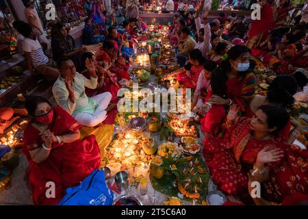 Dhaka, Bangladesh. 4 novembre 2023. Les dévots hindous s'assoient avec Prodip (lumières) et prient Dieu pour le bien-être de la famille devant le temple Shri Shri Lokanath Brahmachari Ashram, Swamibag, Dhaka pendant le Kartik Brati ou Rakher Upobash, un festival religieux hindou de jeûne organisé chaque année à la dernière moitié du mois bengali Kartik. Les dévots s'assoient avec de la nourriture et des bougies et prient sincèrement le Dieu avant de rompre le jeûne. Lokenath Brahmachari qui est appelé Baba Lokenath était un saint hindou du 18e siècle et philosophe au Bengale. Les dévots de Lokenath Brahmachari prient avec lumière pour sauver leur famille Banque D'Images